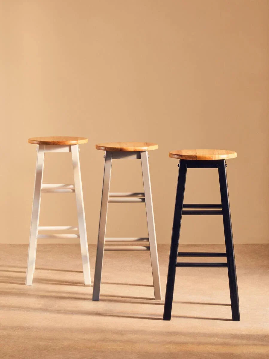 Set of three wooden bar stools with white, grey, and black legs on neutral background