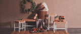 Wicker storage basket with cushion, woven stools, wrapped gifts, and holiday wreath