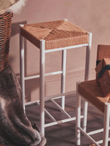 Woven seat bar stool with white legs in rustic home interior setting