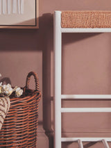 White towel ladder with rope detailing beside brown wicker storage basket and wall art