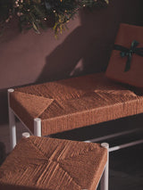 Brown woven bench and matching stool with white metal frame in festive setting