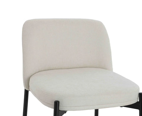 Cream upholstered dining chair with black metal legs, close view of seat and backrest