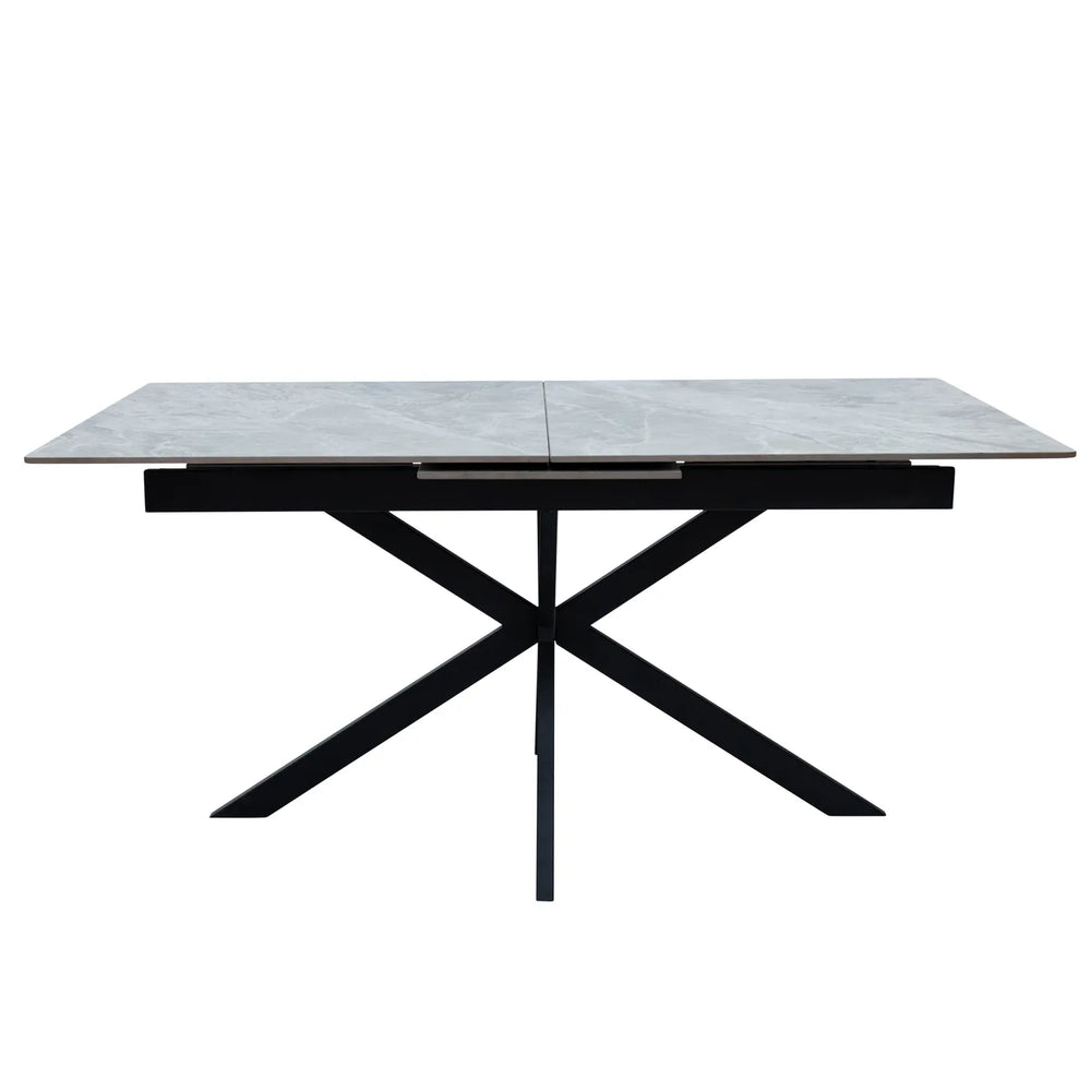 A modern rectangular dining table with a light gray stone-look top and a black metal X-shaped base, shown against a plain white background.