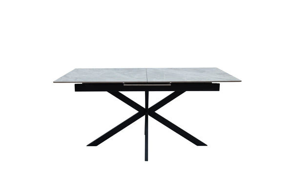 A modern rectangular dining table with a light gray stone-look top and a black metal X-shaped base, shown against a plain white background.