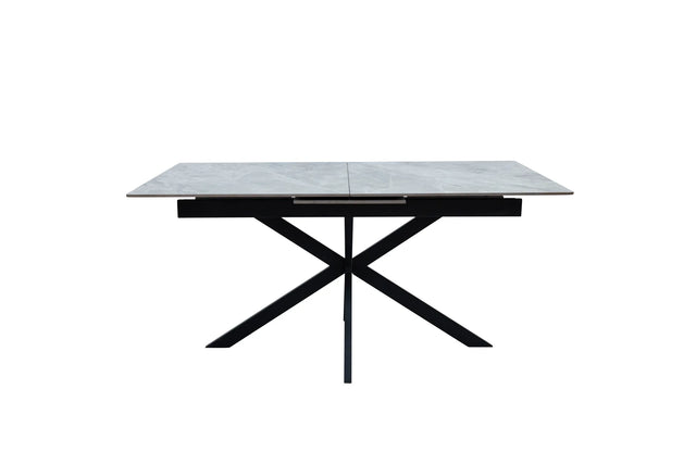 A modern rectangular dining table with a light gray stone-look top and a black metal X-shaped base, shown against a plain white background.