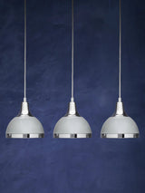 Set of three chrome pendant lights with white shades against a dark blue background