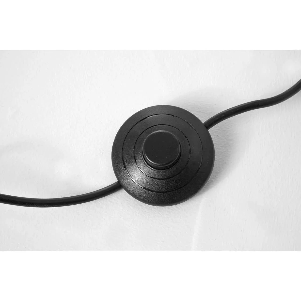 Black floor lamp foot switch with circular design on white surface