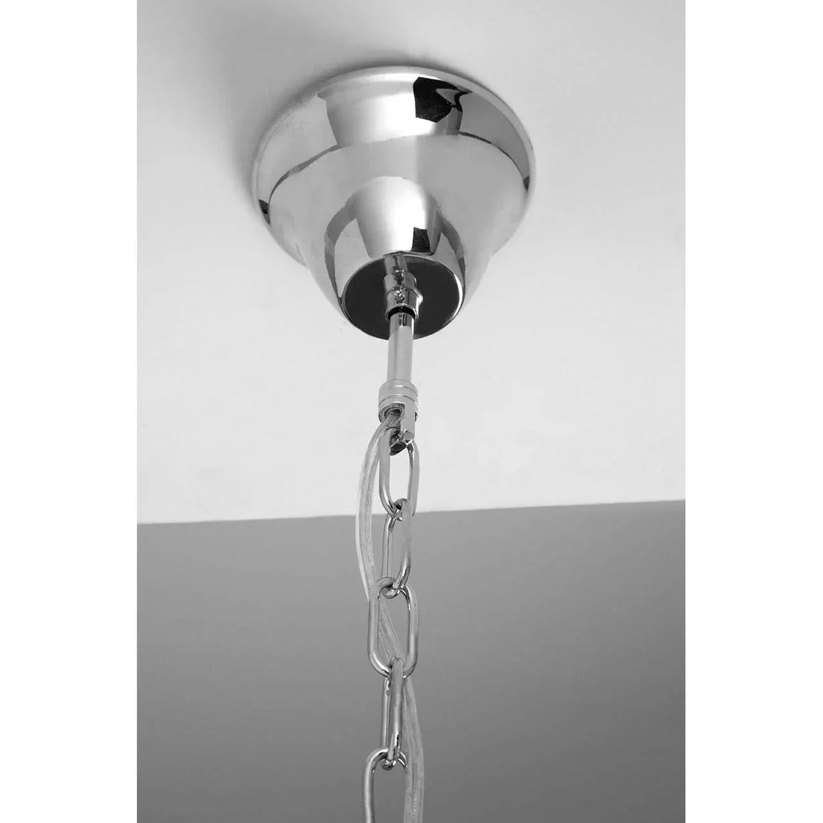 Chrome ceiling light fitting with metal chain and cable detail, close-up view