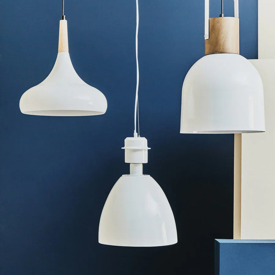 Modern white pendant lights with wood accents hanging against a navy blue wall