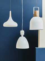 Modern white pendant lights with wood accents hanging against a navy blue wall