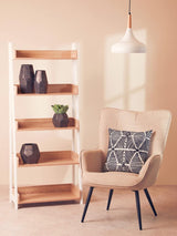 Beige accent chair with geometric cushion beside wooden shelving unit and pendant light
