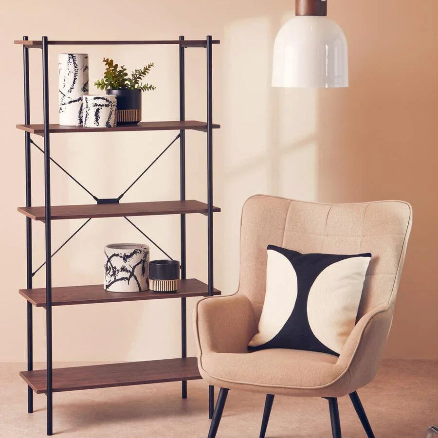 Beige accent chair with black and white cushion beside wooden shelving unit and pendant light
