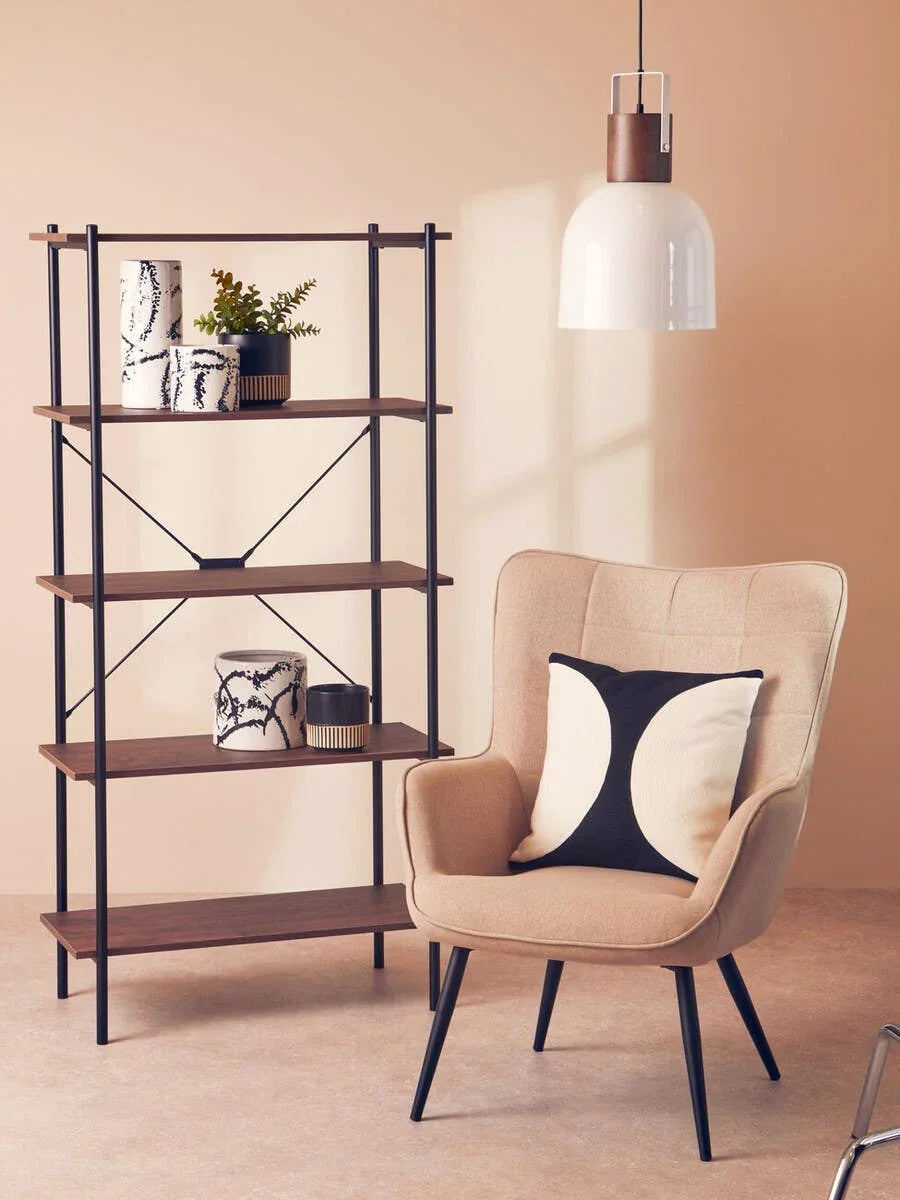 Beige accent chair with black and white cushion beside wooden shelving unit and pendant light
