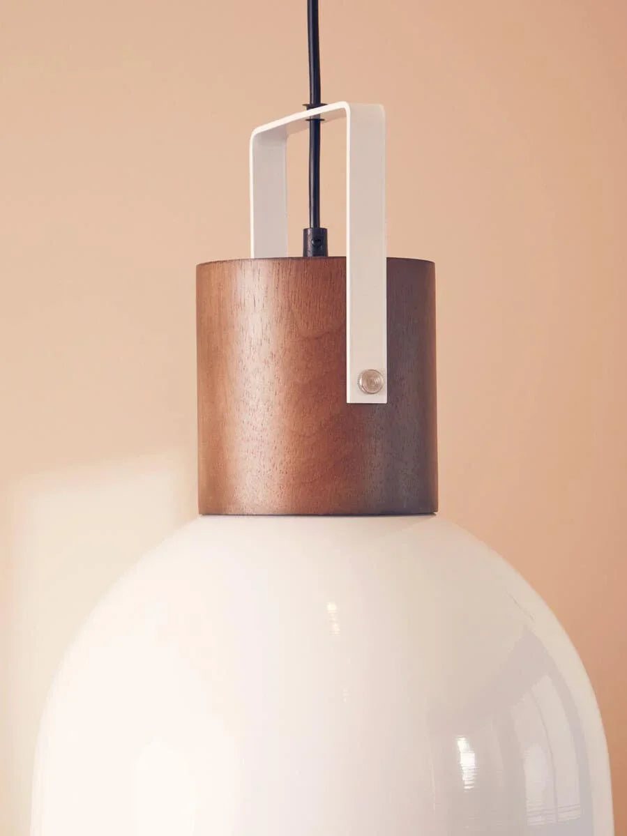 Modern ceiling pendant light with white glass shade and wood detail against beige wall