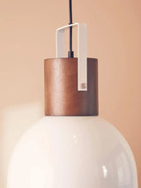 Modern ceiling pendant light with white glass shade and wood detail against beige wall
