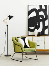 Green upholstered accent chair with black metal legs in modern living room setup