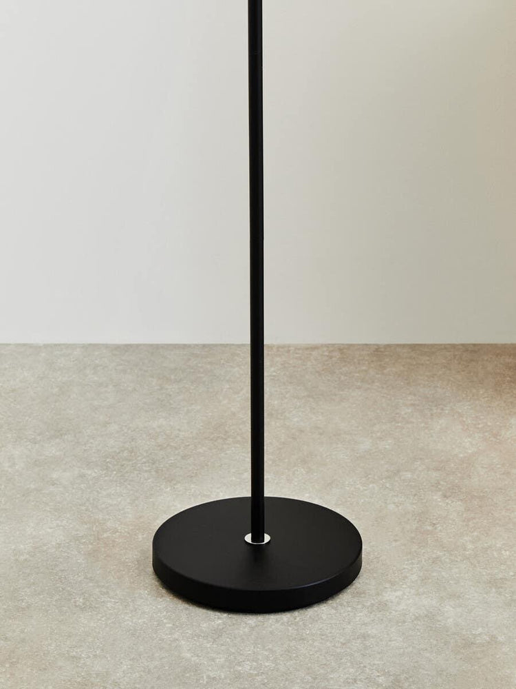 Black metal floor lamp base on neutral tile flooring