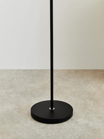 Black metal floor lamp base on neutral tile flooring