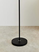 Black metal floor lamp base on neutral tile flooring