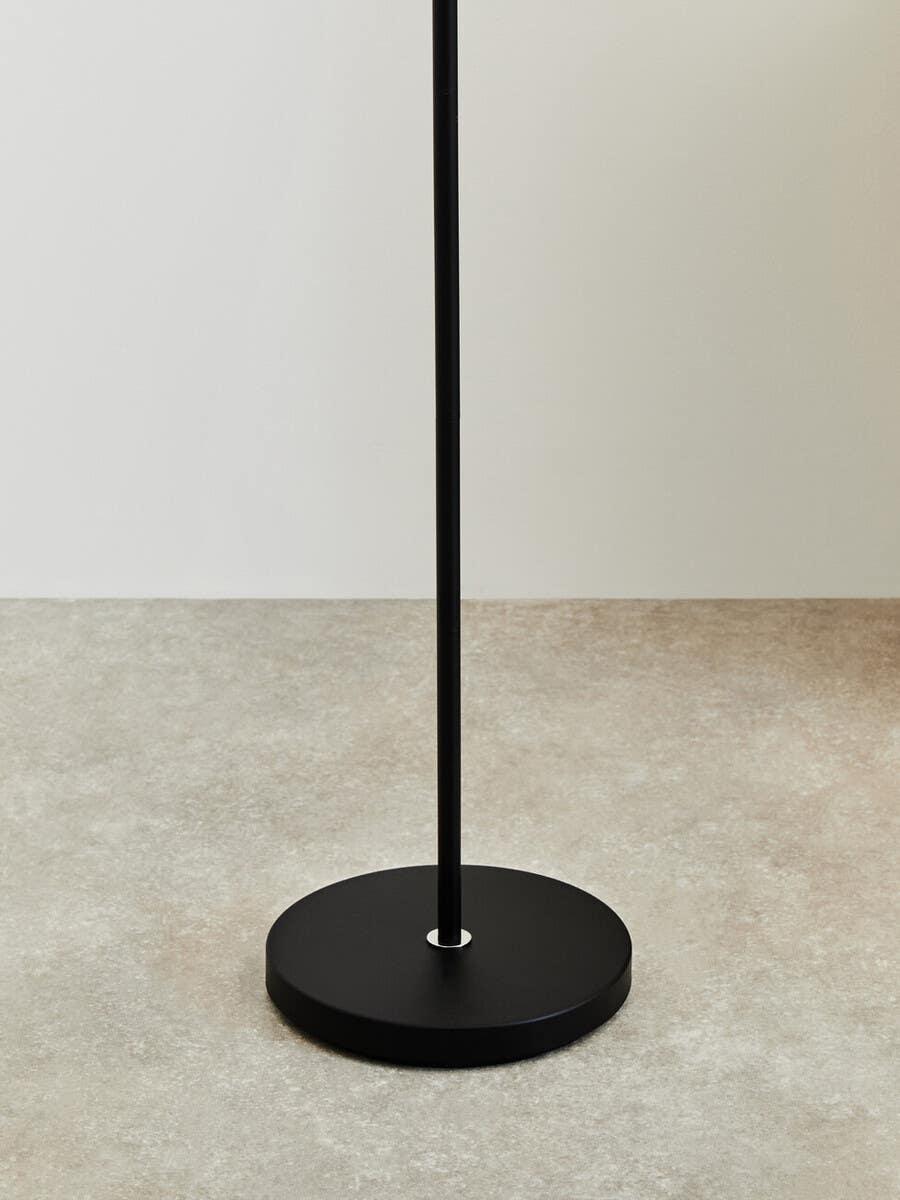 Black metal floor lamp base on neutral tile flooring