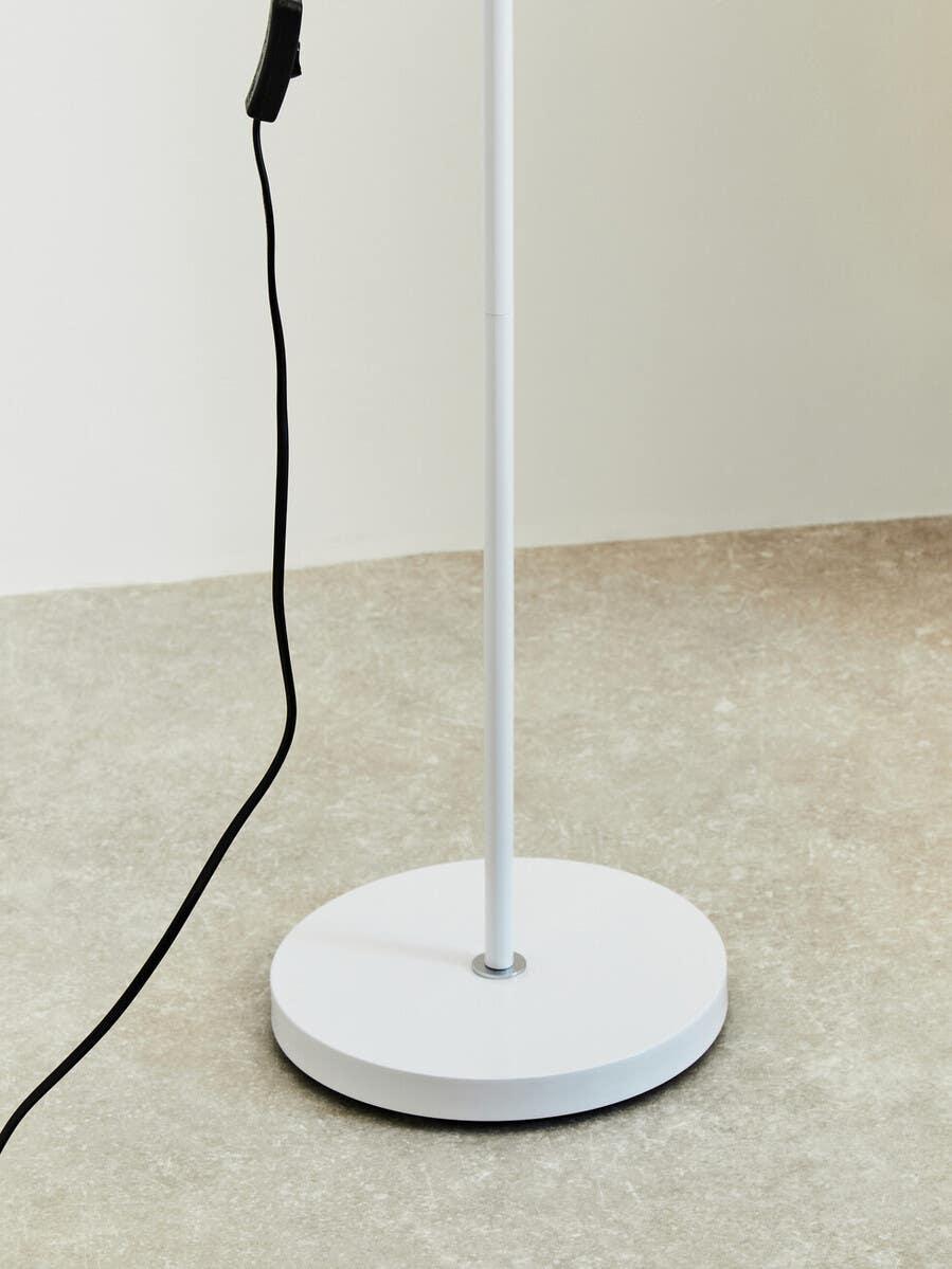 White floor lamp base with power cord on light stone flooring