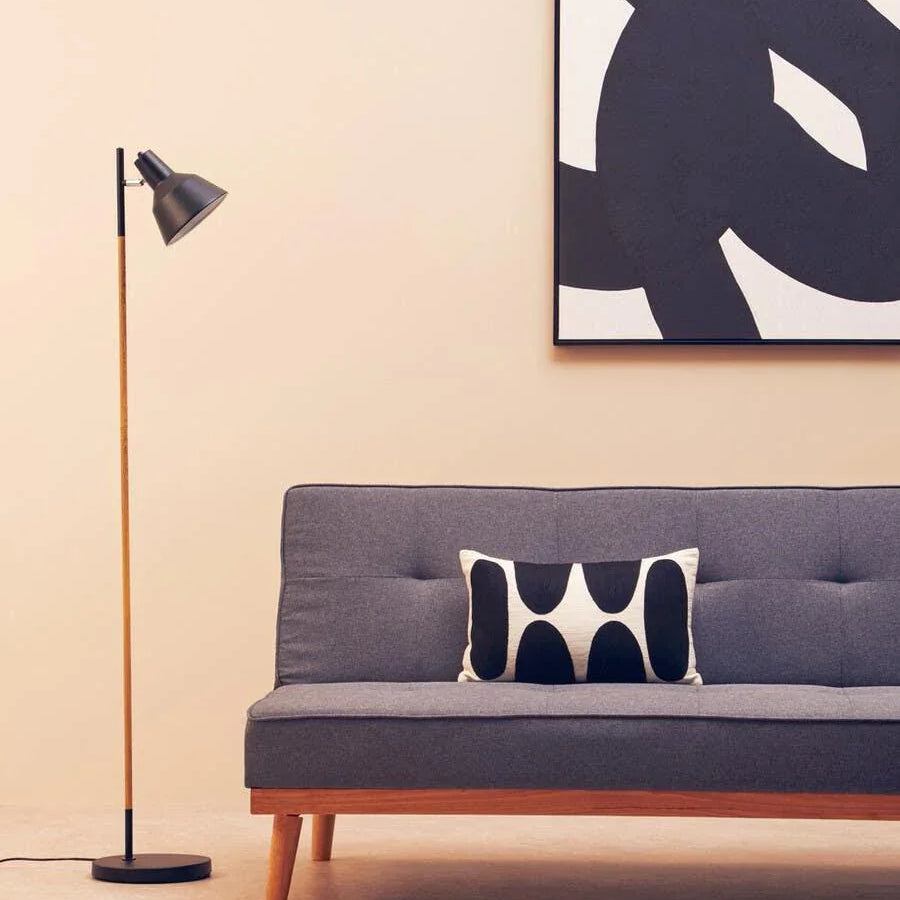 Grey fabric sofa with wooden legs, black and white cushion, floor lamp, abstract wall art