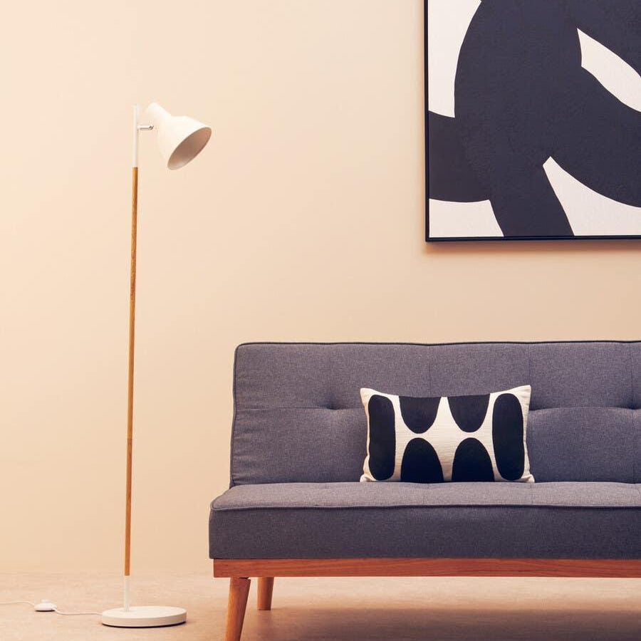 Grey fabric sofa with wood legs, monochrome cushion, floor lamp, abstract wall art