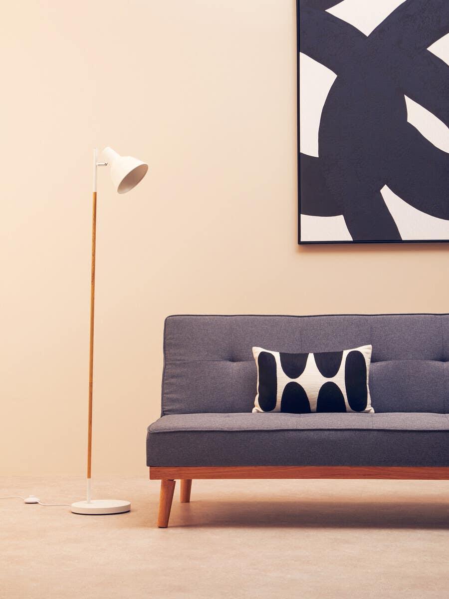 Grey fabric sofa with wood legs, monochrome cushion, floor lamp, abstract wall art