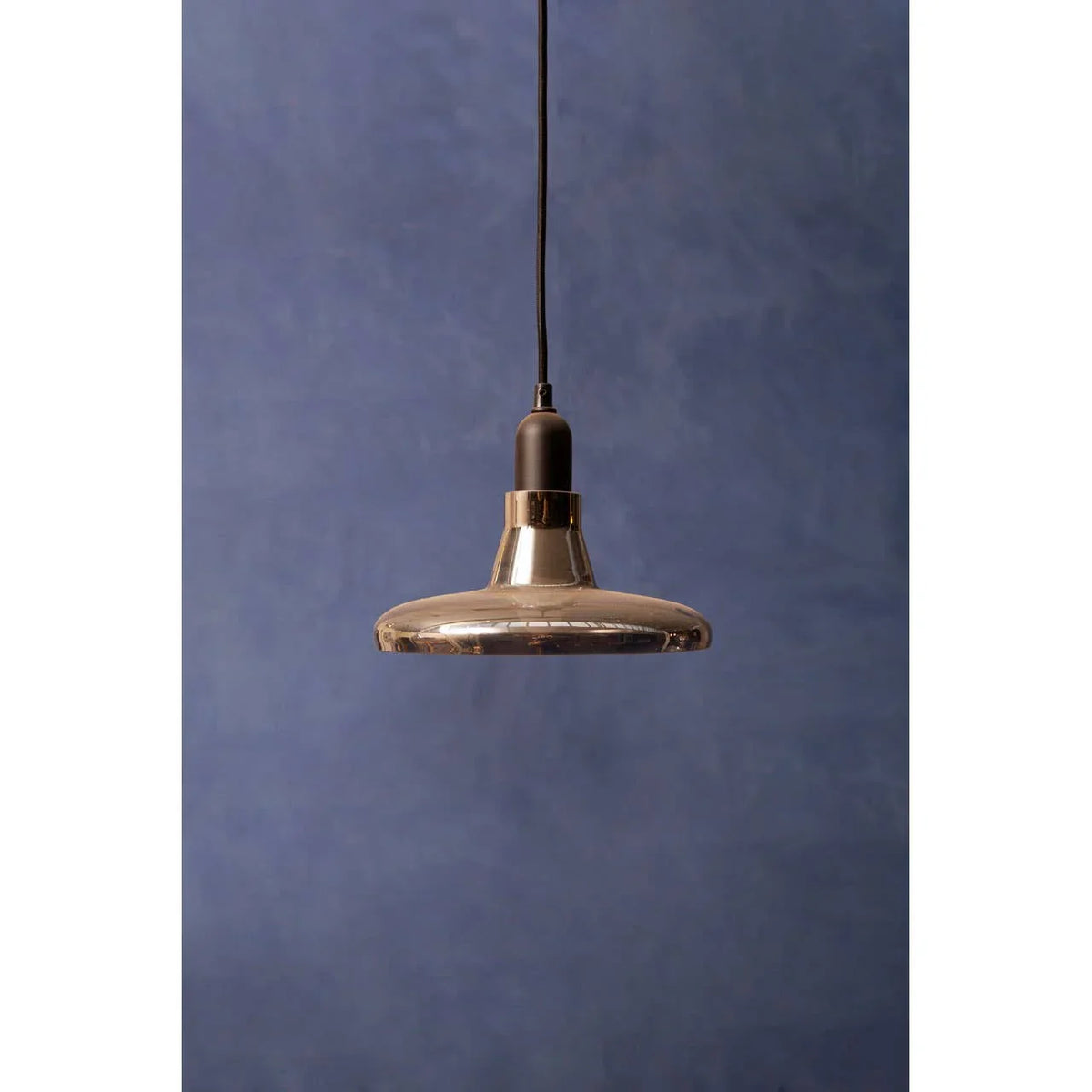 Modern glass pendant light with black fitting against a blue textured wall