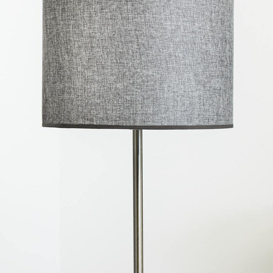 Grey fabric floor lamp with drum shade and metal stand against a white wall