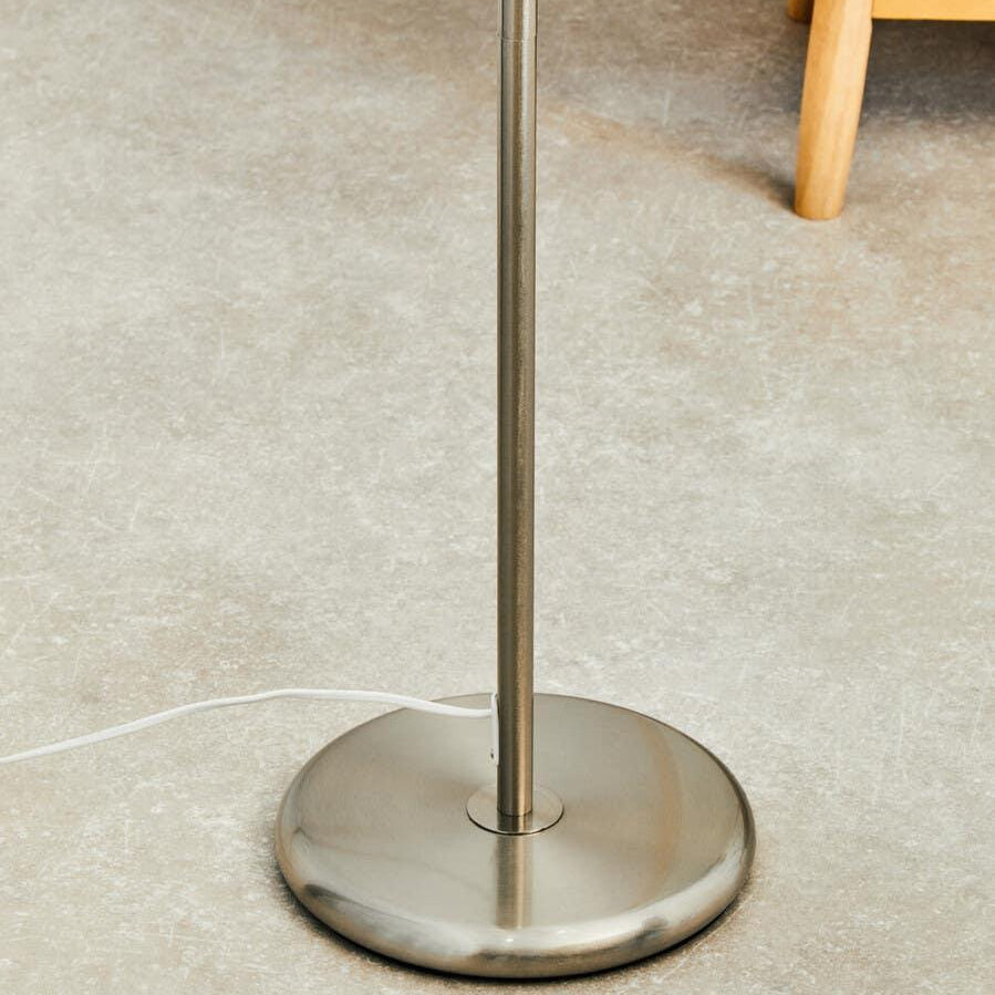 Brushed steel floor lamp base with power cable on stone effect flooring
