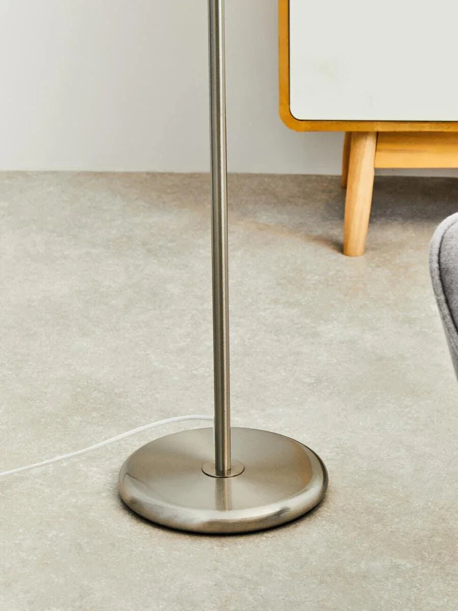 Brushed metal floor lamp base with slim pole on neutral tiled flooring