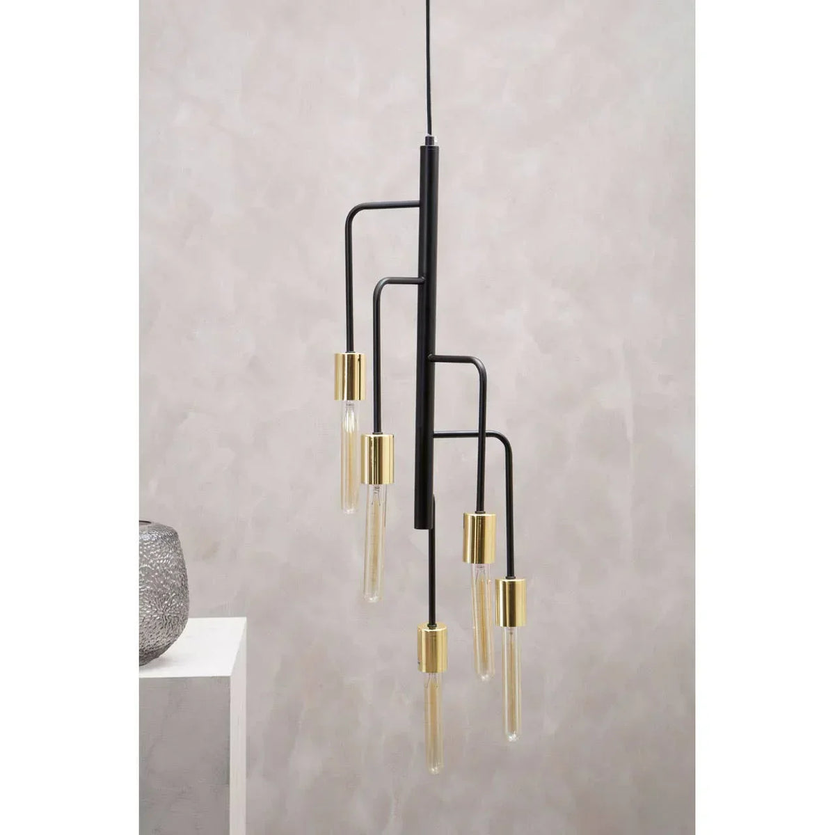 Modern black and gold pendant light fixture with five glass bulbs against neutral wall
