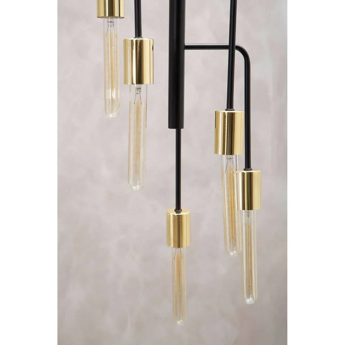 Modern pendant light with gold fittings and tubular bulbs against a neutral backdrop