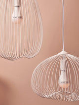 White wire pendant ceiling lights with exposed bulbs against a blush pink wall