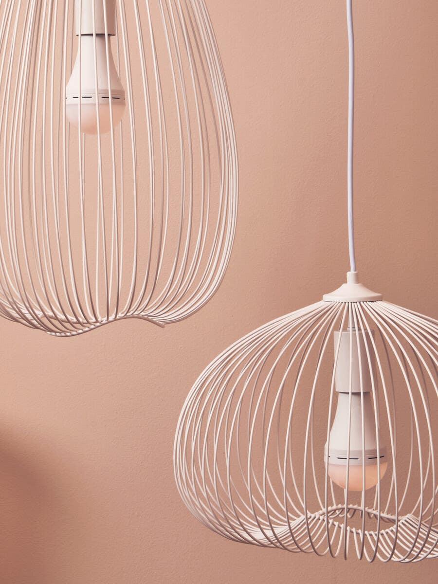 White wire pendant ceiling lights with exposed bulbs against a blush pink wall