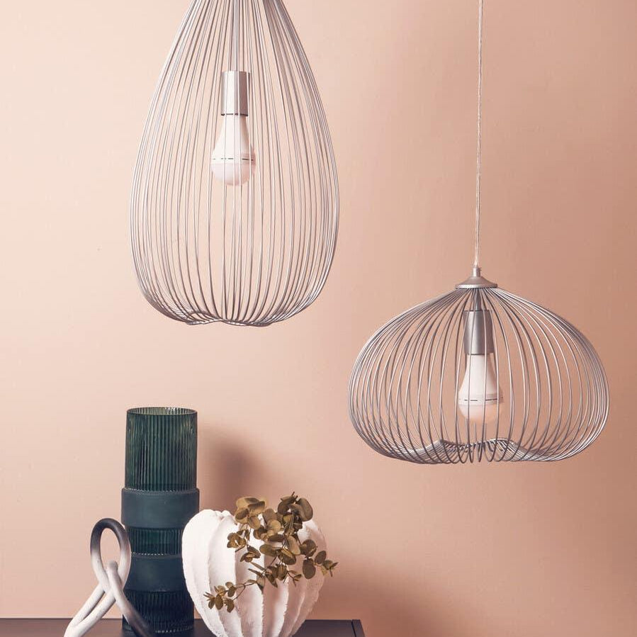 Modern wire pendant ceiling lights above black console table with green vase and white planter