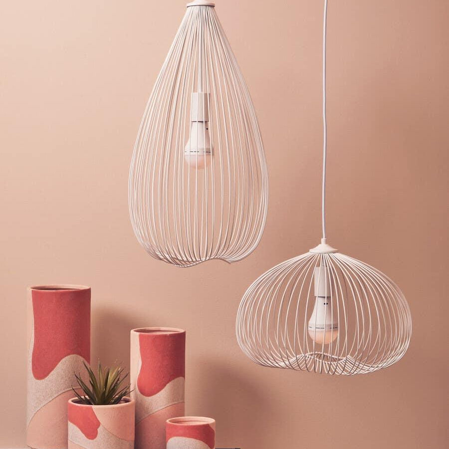 Modern white wire pendant light fixtures above ceramic plant pots on black console table