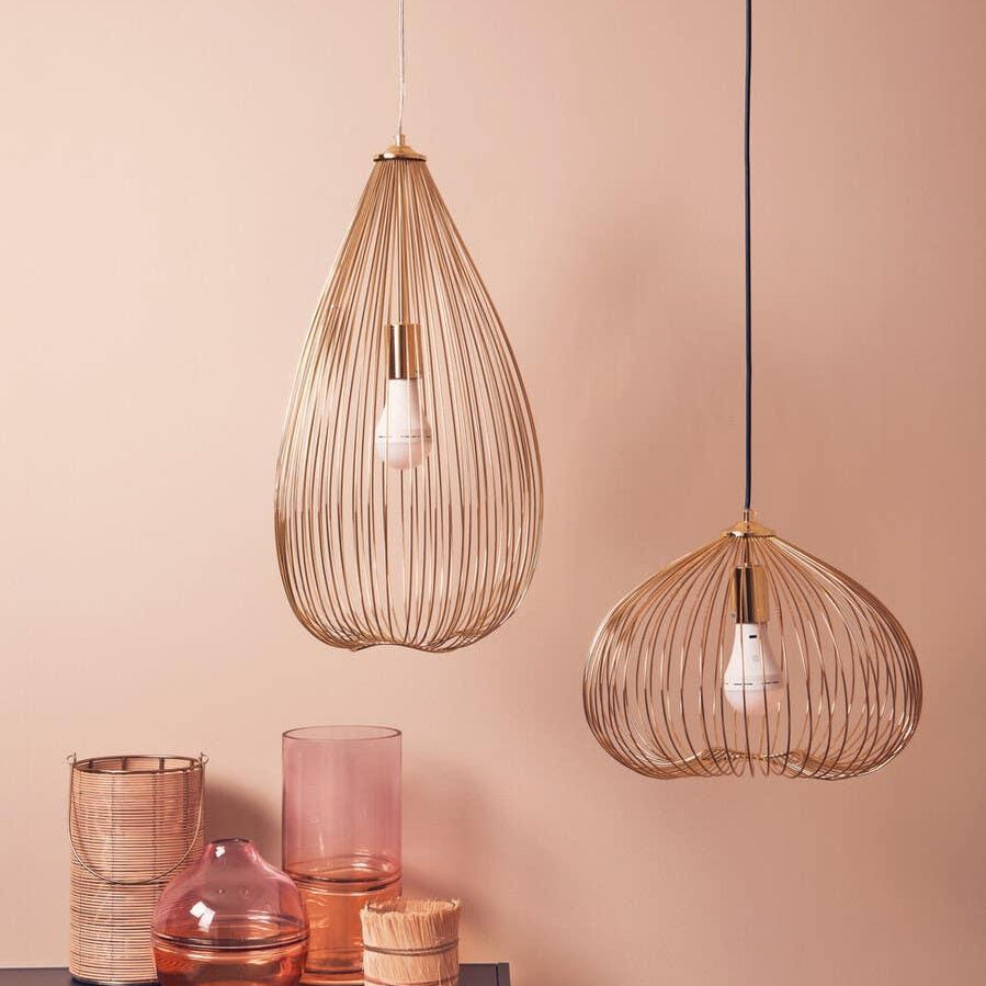 Gold wire pendant lights above pink glass vases on shelf, modern home decor setup
