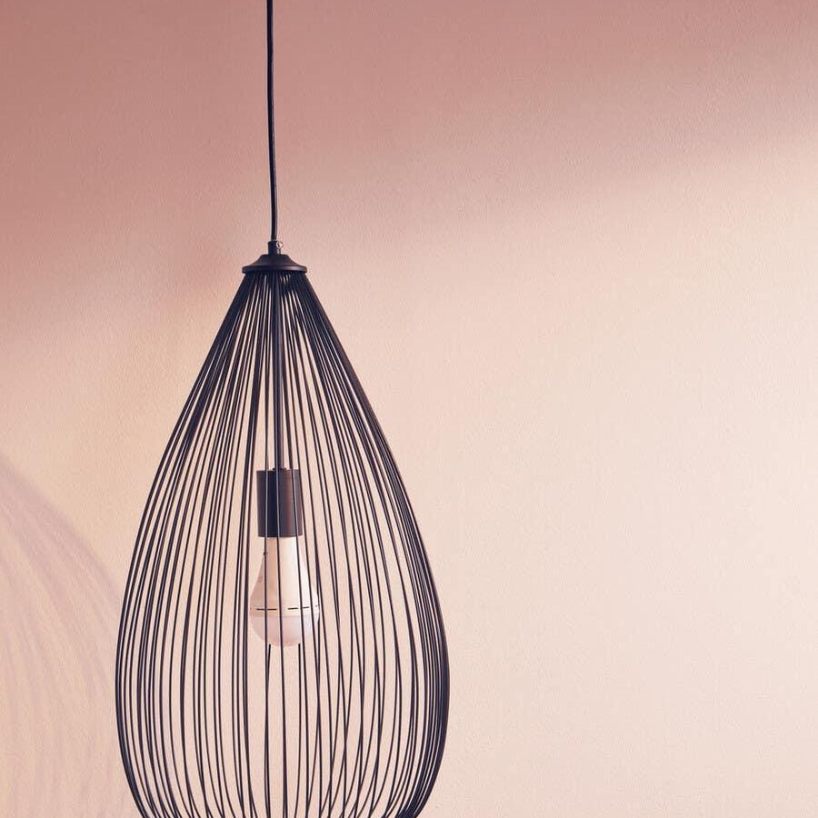 Black wire pendant light with exposed bulb against a neutral wall