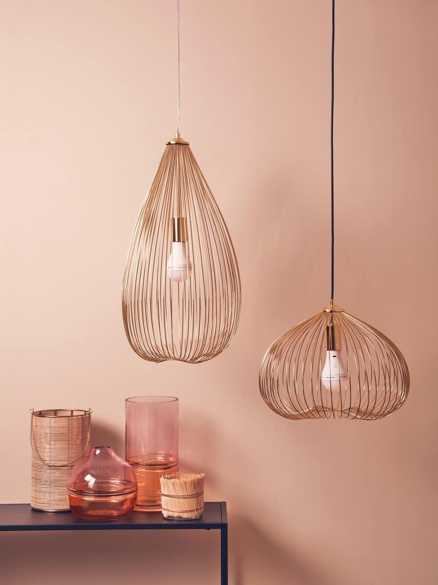 Gold metal pendant lights with exposed bulbs above glass vases on a black console table