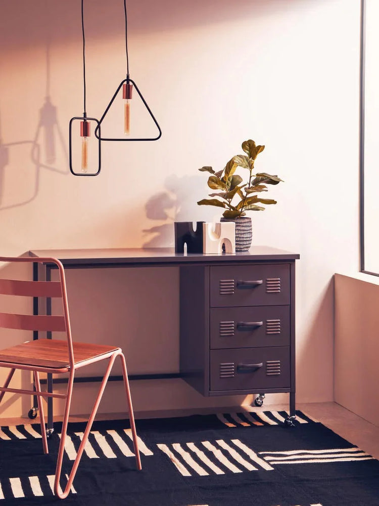 Metal office desk with three drawers, modern chair and plant on patterned black rug
