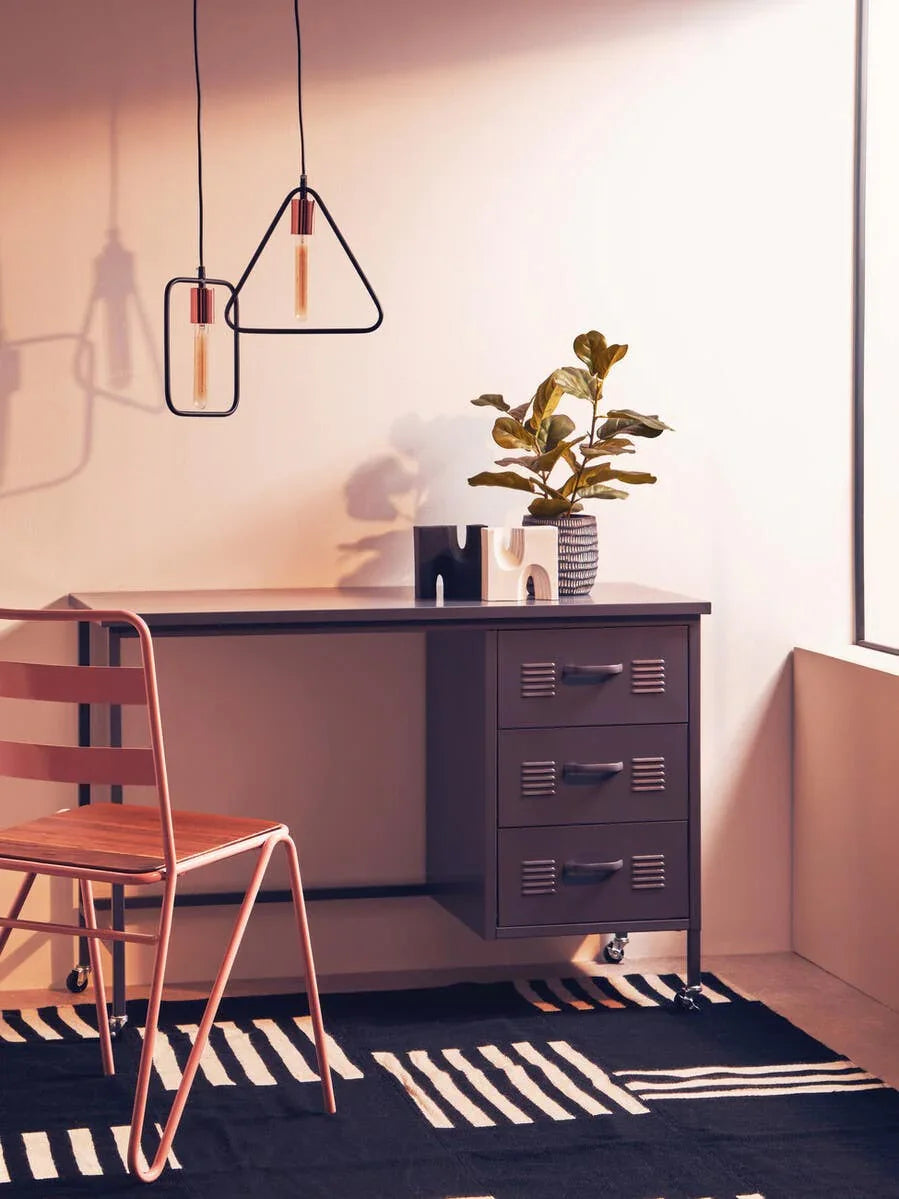Metal office desk with three drawers, modern chair and plant on patterned black rug
