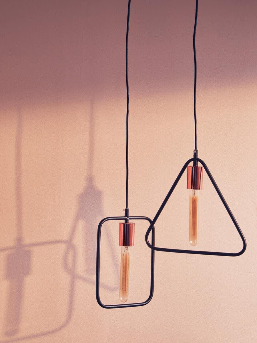 Modern pendant lights with copper fittings and exposed bulbs against a neutral wall
