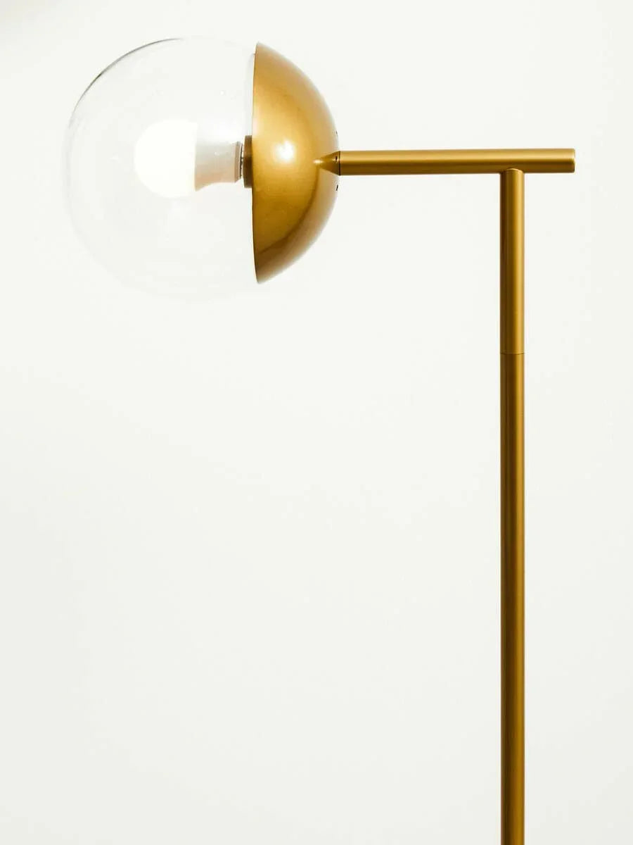 Gold floor lamp with clear glass globe shade and minimalist metal frame