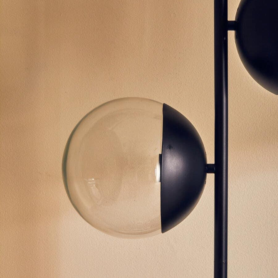 Modern black and glass floor lamp globe detail against beige wall