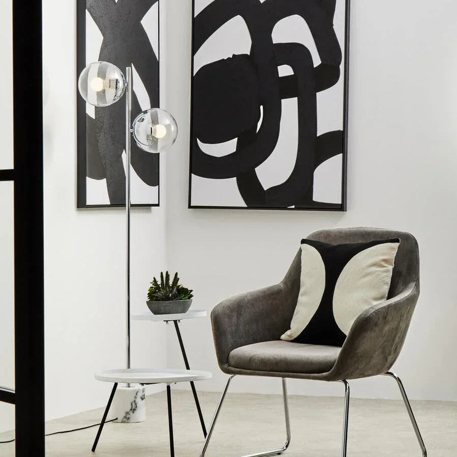 Grey accent chair with curved arms, black and cream cushion, next to modern side table