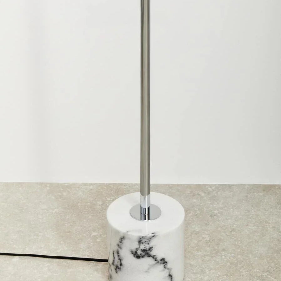 Modern floor lamp with chrome stand and white marble base on tiled floor