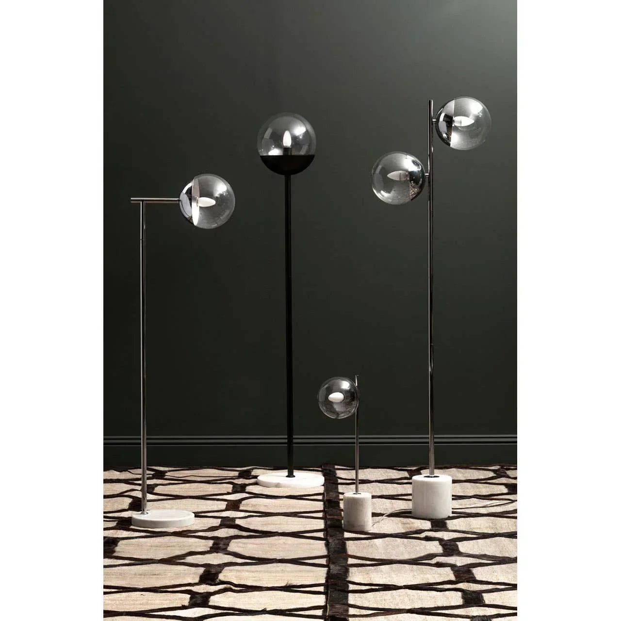 Modern glass globe floor lamps with chrome and marble bases on patterned rug