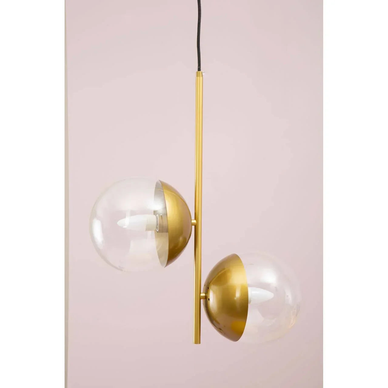Modern pendant light with gold metal rod and two glass globe shades on pink background